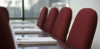 Conference room table with chairs and notepads on table.