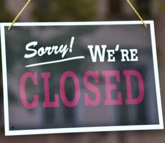 'Closed' sign hanging from glass door entrance.