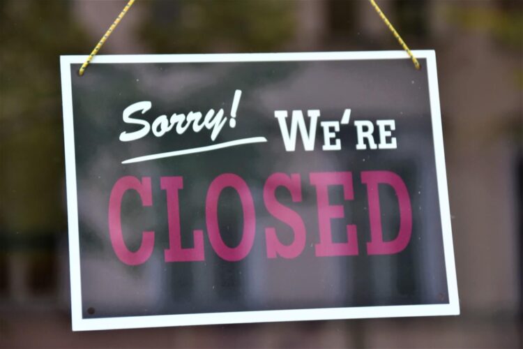 'Closed' sign hanging from glass door entrance.