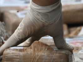 Latex gloves hand handles cocaine in brown packages.