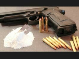 Small pile of cocaine next to a handgun and bullets.