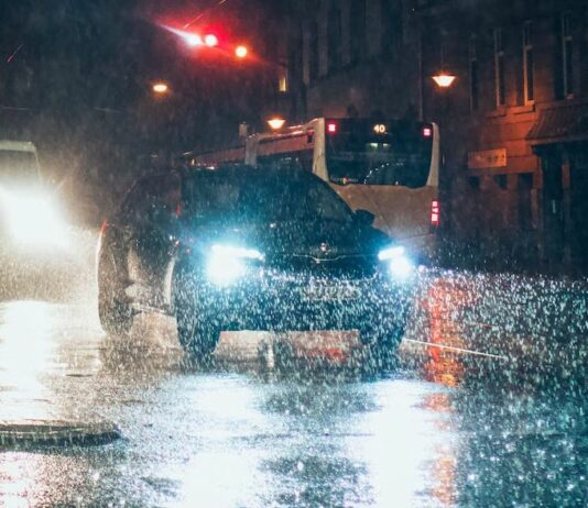 Vehicles on the road at night while the rain falls.