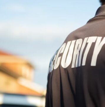 Security guard with back to camera wearing polo shirt marked 'Security'.