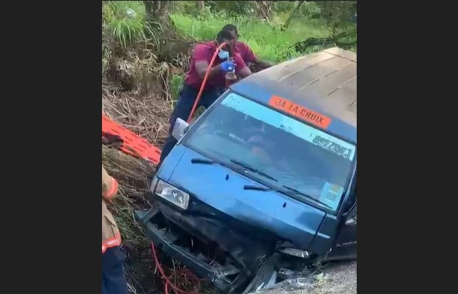 Firefighter using extrication tool to free accident victim trapped in mangled metal of a minibus.