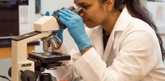 Female laboratory technician peers into a microscope