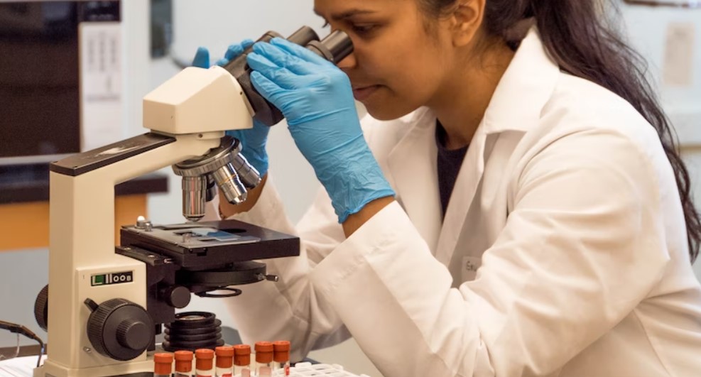 Female laboratory technician peers into a microscope