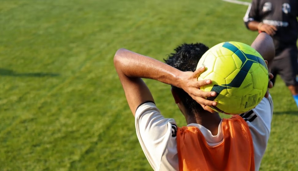 Soccer player on sideline prepares to throw ball into play.