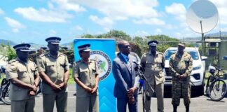 Prime Minister Philip J. Pierre addresses ceremony to hand over new vehicles to the police while senior officers stand behind him.