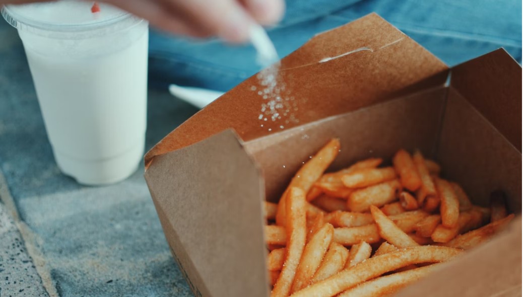 Salt being sprinkled on box of potato chips