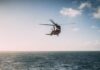 Search and rescue helicopter flying over choppy sea.