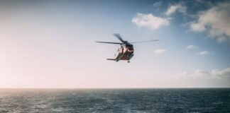 Search and rescue helicopter flying over choppy sea.