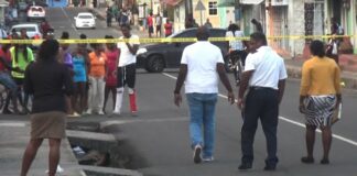 Police tape and crowd at scene of Vieux Fort murders