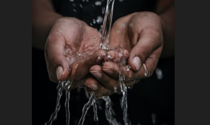 Water flowing into someone's hands from a pipe.