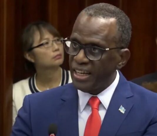 Philip J. Pierre delivering budget address to parliament with Taiwanese Ambassador and wife in the background.
