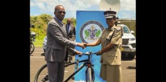 Prime Minister Philip J. Pierre and Police Commissioner Crusita Descartes-Pelius shake hands as he hands over a bicycle as part of a gift of resources in the fight against crime.