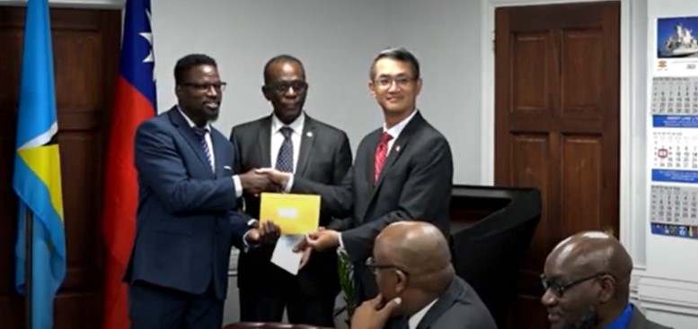 Taiwan's ambassador presents cheque for constituency development programme in Saint Lucia while Prime Minister Philip J. Pierre looks on.