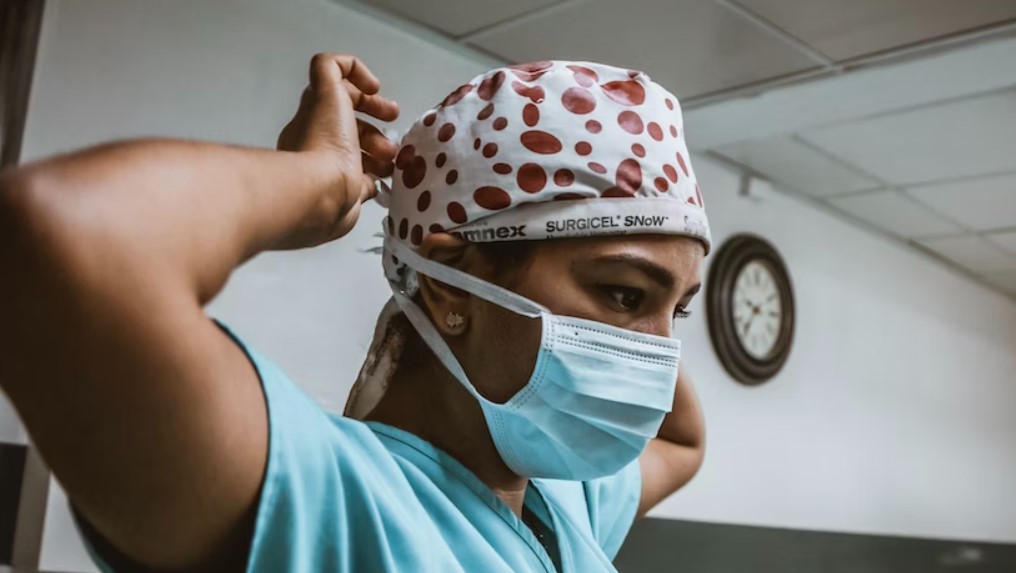 Female nurse putting on surgical mask.