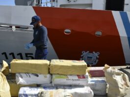 US Coast Guard official stands near bales of cocaine seized from a go-fast vessel off Puerto Rico.