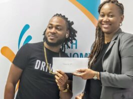 Young Saint Lucian entrepreneur receives funding from Youth Economy Agency representative to finance his business.