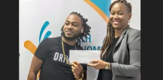 Young Saint Lucian entrepreneur receives funding from Youth Economy Agency representative to finance his business.