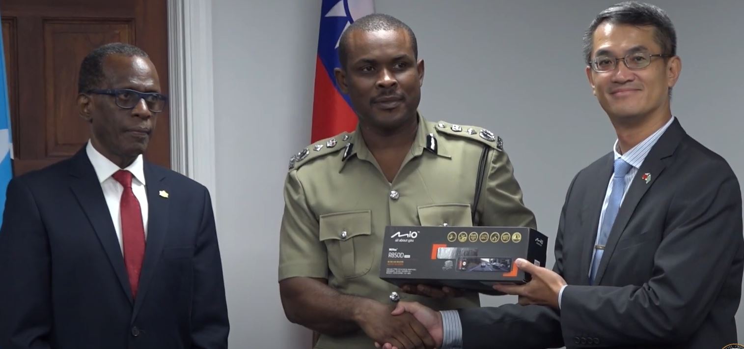 Taiwan Ambassador Peter Chen hands over surveillance equipment to Acting Police Commissioner Ronald Phillip while Prime Minister Philip J. Pierre looks on.