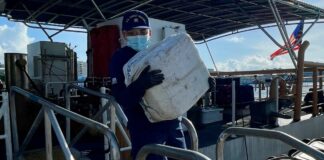 US Coast Guard officer offloads bale of drugs from vessel.