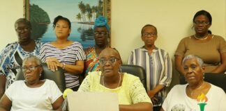 United Workers Party spokeswoman Forruna Belrose, flanked by female party supporters, reads a prepared statement at an opposition news conference.