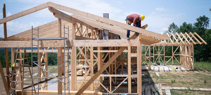 House under construction with man working on roof.