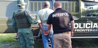 Handcuffed man in the custody of two INTERPOL officers.