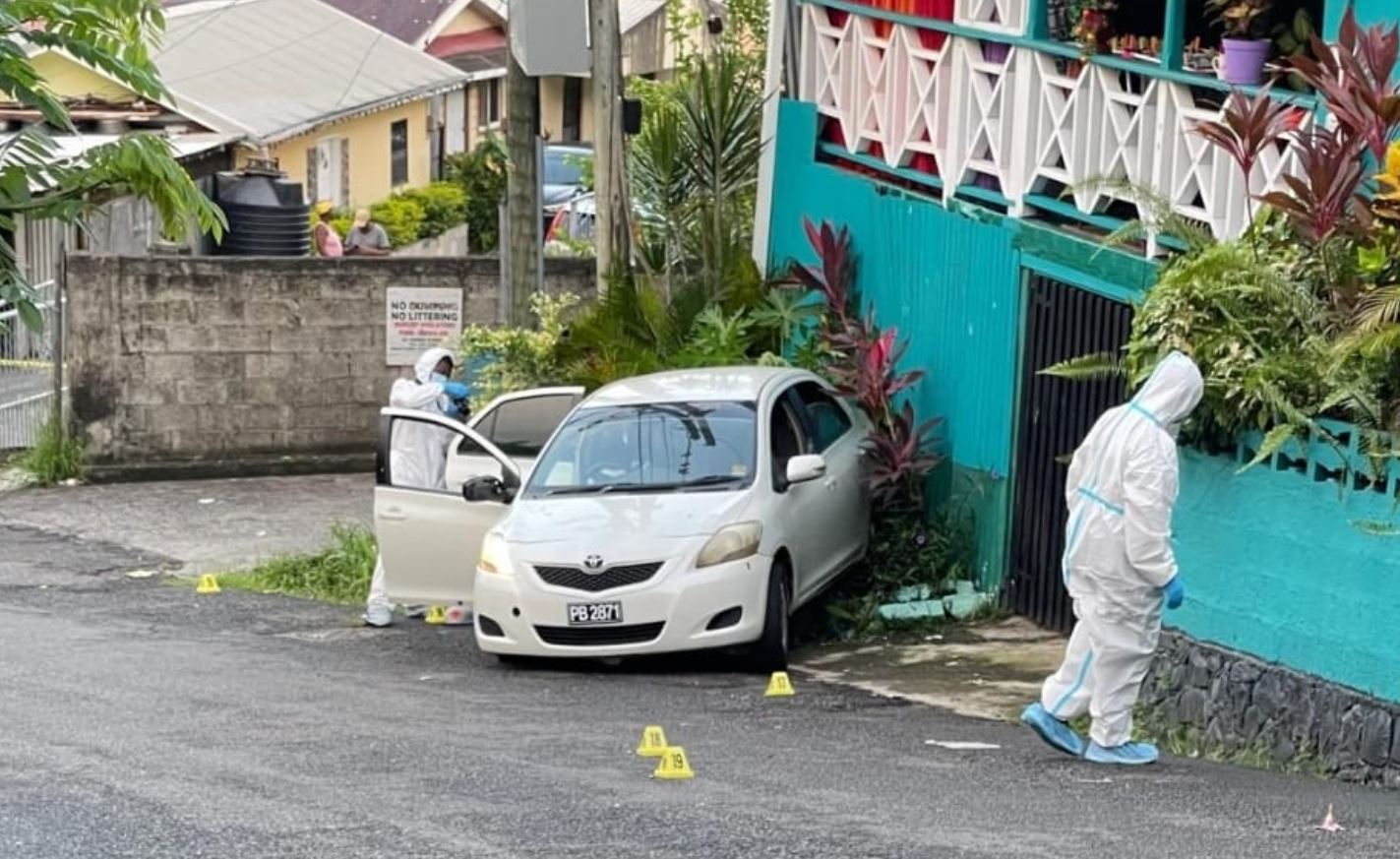 Crime scene investigators in white plastic suits near car in which a man was shot dead in La Clery, Castries.