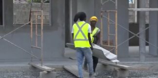 Construction workers moving material on job site.