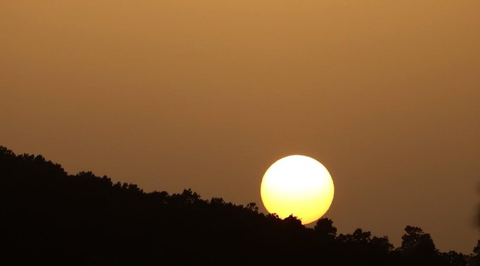 Sun setting in an amber sky due to dust haze.