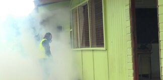 Man wearing safety gear engages in mosquito fogging at a school compound in Saint Lucia.