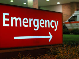 Sign in white letters and arrow against red background pointing the way to a hospital's Accident & Emergency Department .