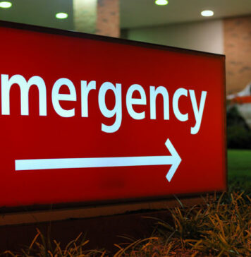 Sign in white letters and arrow against red background pointing the way to a hospital's Accident & Emergency Department .