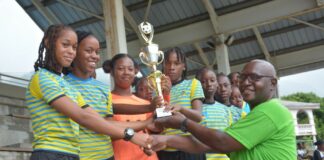 Winning team in girls' football festival receives trophy from match official.