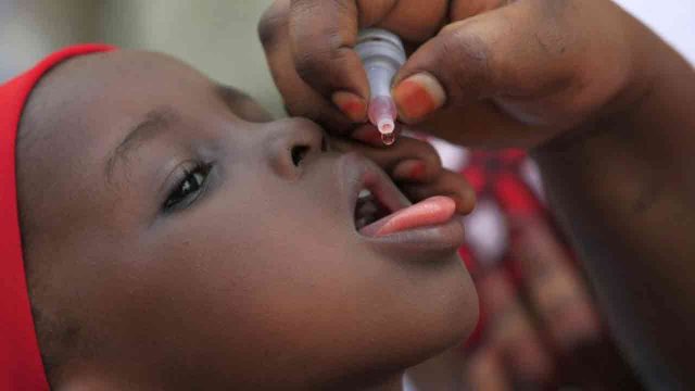 Child being administered polio vaccine by mouth.