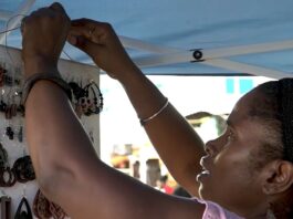 Woman hangs up handicraft at booth in Wilton's Yard, Castries.