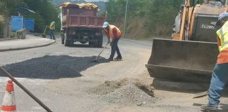 Two workers engage in filling potholes on the road.