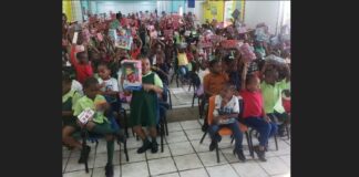 School children in uniform hold up gifts they received from the Sandals Foundation and Hasbro.