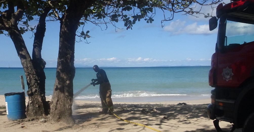 Firefighter putting out almond tree fire at Vigie Beach.
