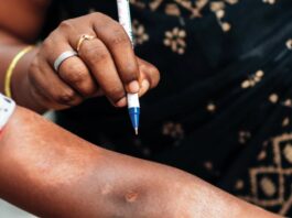 Women using pen to point to a leprosy spot on someone's arm.