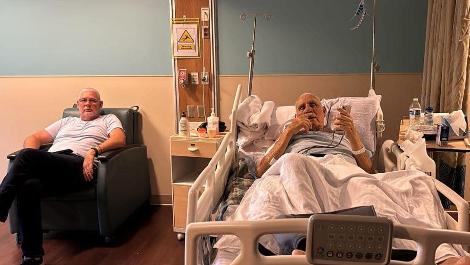 Allen Chastanet sits at his father Sir Michael Chastanet's bedside in a hospital.