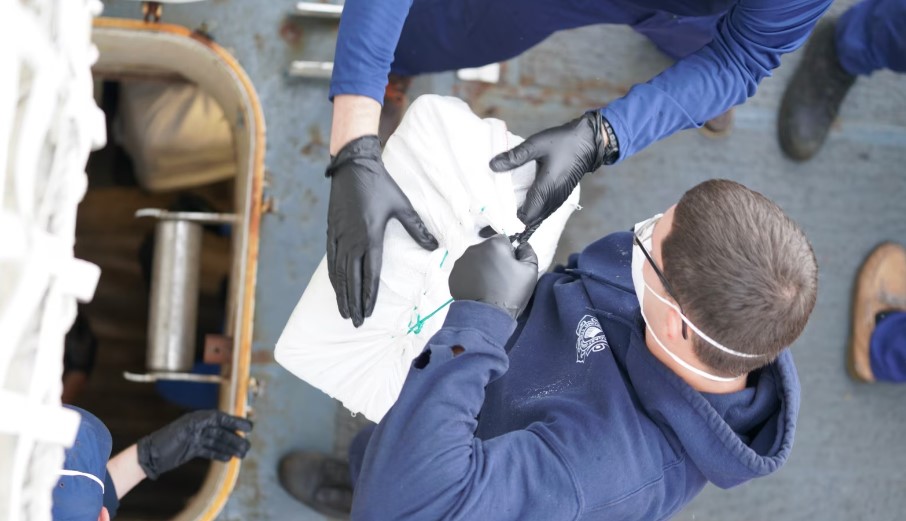 Coast Guard official transfers bale of cocaine from interdicted vessel.