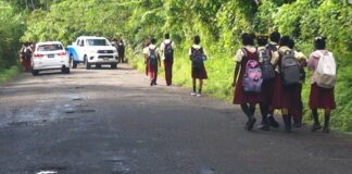 Students walk potholed road in Soufriere-Fond St. Jacques.