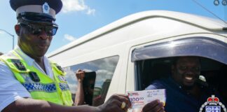 A police officer presents a gist voucher to a motorist.