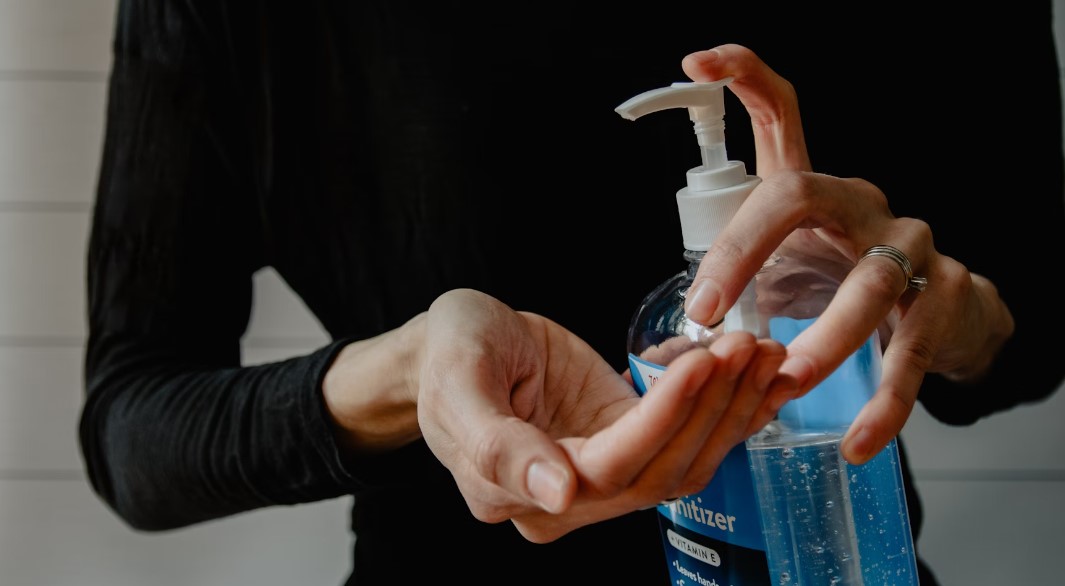 Woman pumps hand sanitizer from a bottle unto one open palm.