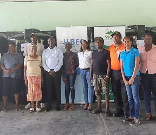 Livestock farmers and Agriculture Minister Alfred Prospere pose with water tanks in the background.