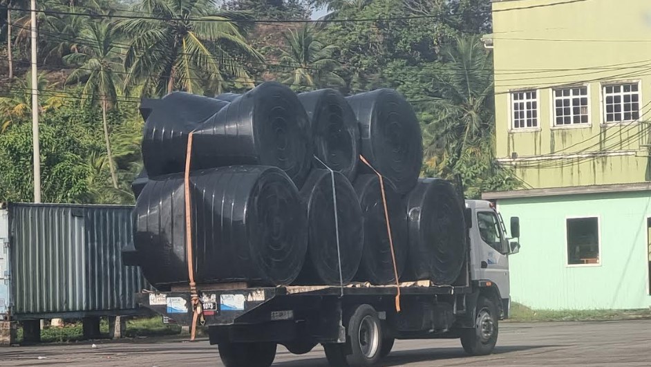 Truck carrying black plastic water tanks.