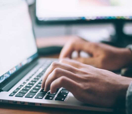 Hands typing at computer